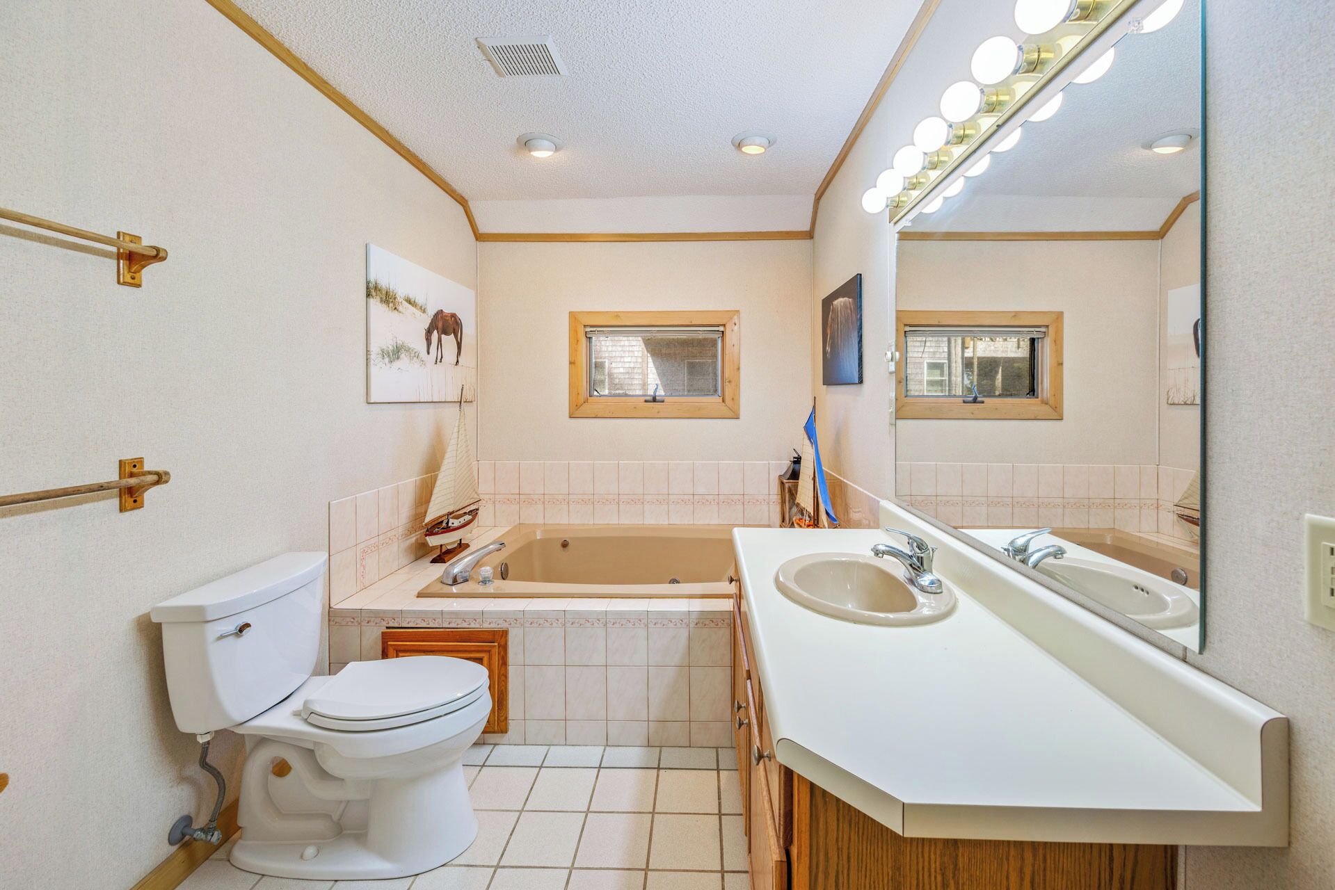A bathroom with a toilet, bathtub, sink, and a large mirror.