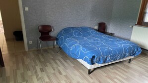 Ein Schlafzimmer mit einem Bett, zwei Stühlen, einem Heizkörper und Holzboden.