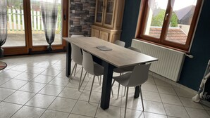 Ein Essbereich mit Holztisch und -stühlen, einem Schrank und Blick durch eine Glastür.