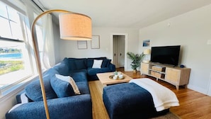 Una sala de estar moderna con un sofá seccional, una mesa de centro, un mueble para televisor y un ventanal con vistas.