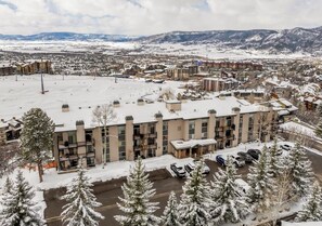 Un hôtel à étages, doté d’un parking et offrant une vue sur un paysage enneigé avec des montagnes en arrière-plan.
