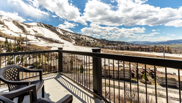A balcony with a view of a snow-covered mountain, a ski lift, and a row of buildings. - Ski-In/Ski-Out Condo with Sweeping Slopeside Views! (Steamboat Springs)