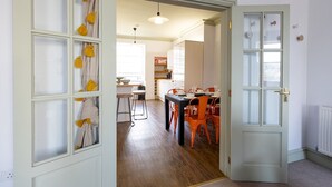 A hallway leading to a dining area with a table set for two, a kitchen area, and a door with frosted glass panels. - Stunning apartment in central location - Pass the Keys (Bath)