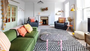 A living room with a green sofa, two armchairs, a patterned rug, and a fireplace. - Stunning apartment in central location - Pass the Keys (Bath)