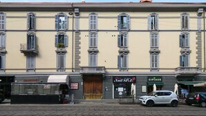 A building with multiple shops on the ground floor, including a nail salon and a pharmacy. - Sweett | Corso Como III (Milano)