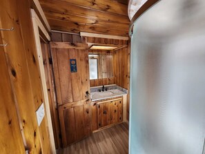 L'intérieur d'un chalet en bois comprend une salle de bain équipée d'un lavabo et d'un miroir.