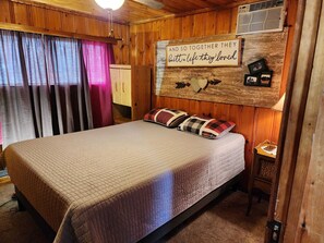 Une chambre confortable avec un lit, une tête de lit en bois, un climatiseur fixé au mur et un panneau décoratif.