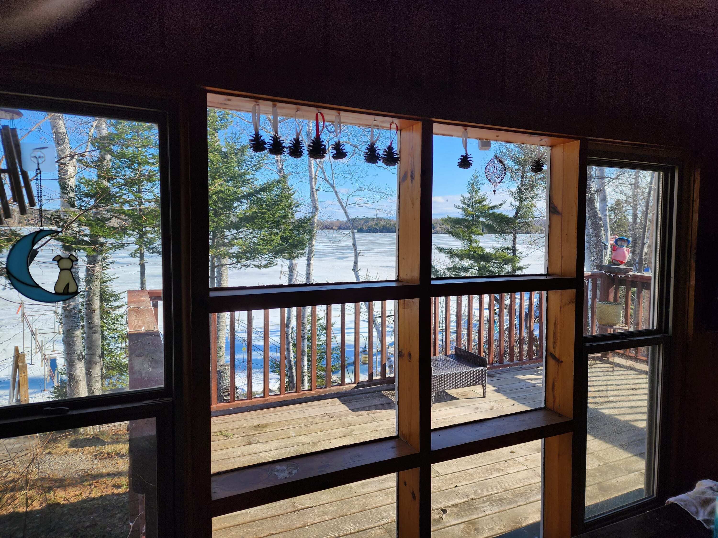 A room with a large window overlooking a wooden deck and a snowy landscape.