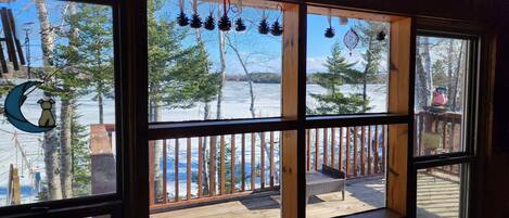 A room with a large window overlooking a wooden deck and a snowy landscape.