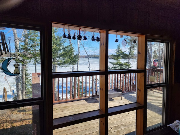 A room with a large window overlooking a wooden deck and a snowy landscape.