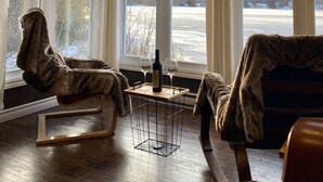 Una habitación acogedora con ventanas amplias, techo de madera y dos sillones cubiertos de piel.