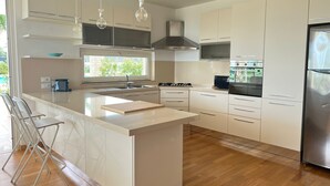 Una cocina moderna con una isla grande, electrodomésticos de acero inoxidable y vistas a zonas verdes.