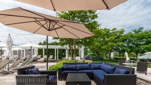 Un espace extérieur aménagé avec des meubles en osier, une table et des parasols.
