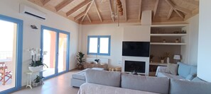 Un salon moderne avec un grand canapé gris, un téléviseur à écran plat et un plafond en bois.