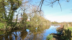 A calm river with reflections of trees and a wooden fence on the right. - 1 The Dell (Norwich)