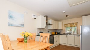 A modern kitchen with wooden cabinets, a built-in oven, and a stainless steel refrigerator. - 1 The Dell (Norwich)