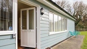 A light blue house with a white front door, a small porch, and a potted plant. - 1 The Dell (Norwich)
