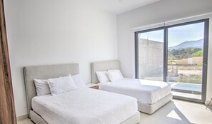 A modern bedroom with two beds, large windows, and a view of the outdoors.
