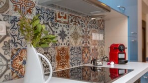 Una cocina con encimera blanca, una cafetera roja y un salpicadero decorado con azulejos.