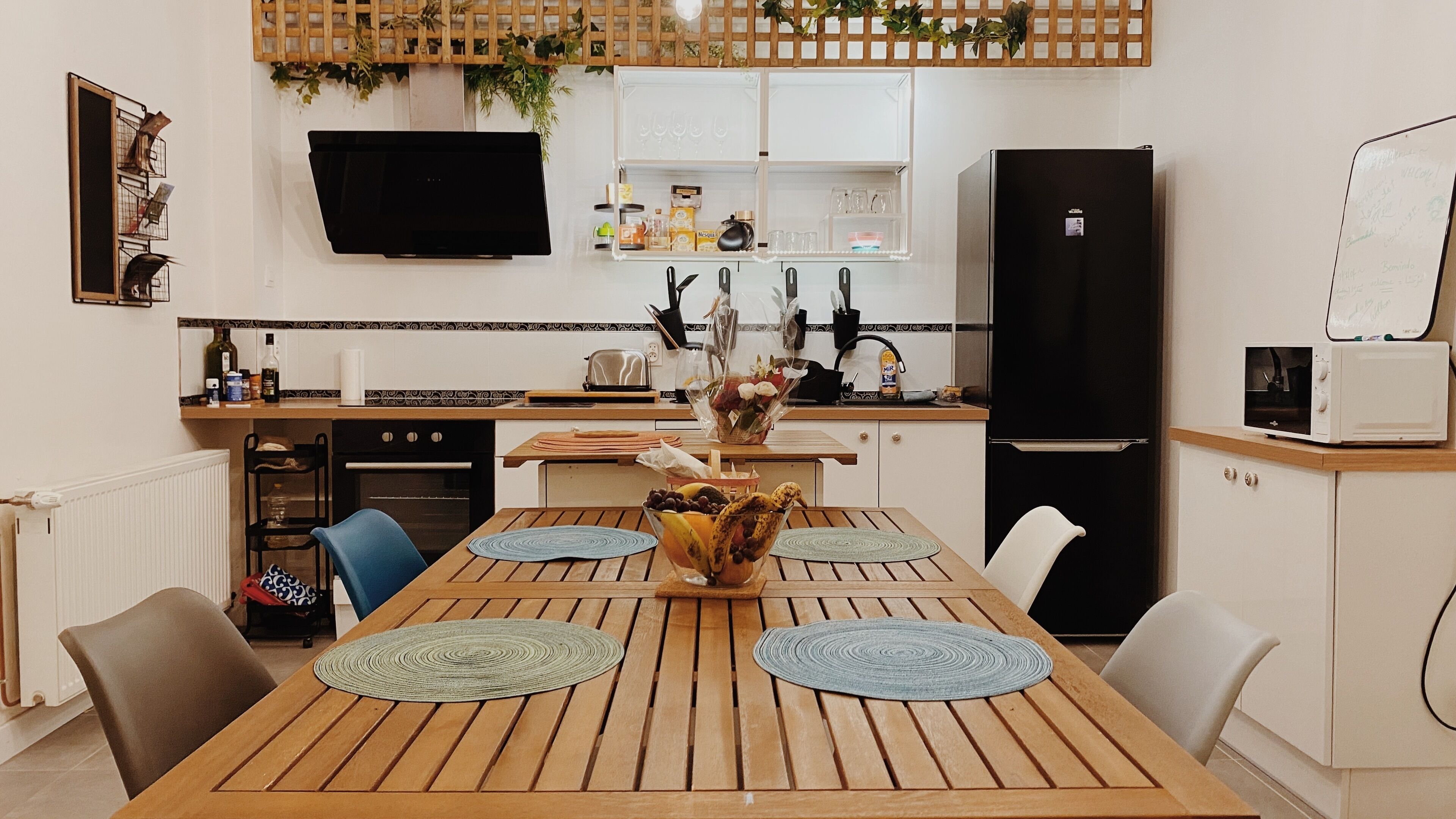 A modern kitchen with a dining table, chairs, and a refrigerator.