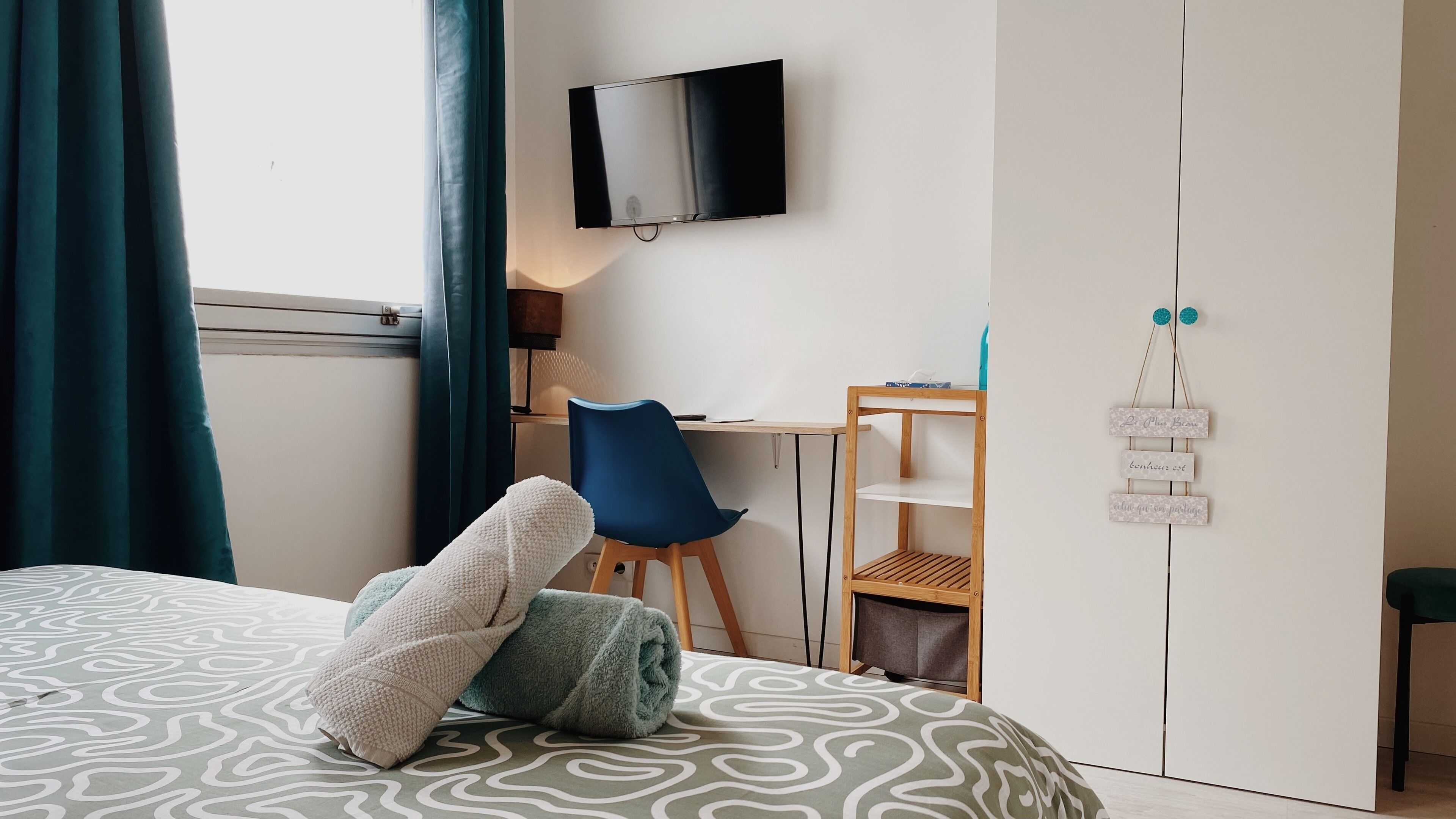 Une chambre à coucher comprenant un lit, un bureau, une chaise, une armoire et un téléviseur fixé au mur.