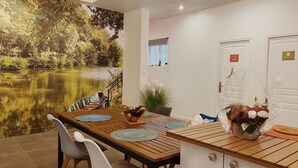 Un comedor con mesa de madera, sillas y vistas a un estanque a través de un ventanal amplio.