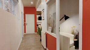 Un pasillo estrecho con una pared roja, una puerta blanca y un radiador blanco.