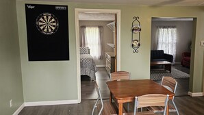 Een eethoek met een tafel en stoelen, een dartbord en een bed met beddengoed met een patroon op de achtergrond.