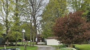 Een oprit van een woning met een aangelegde tuin, een brievenbus en een aanhangwagen aan de zijkant.