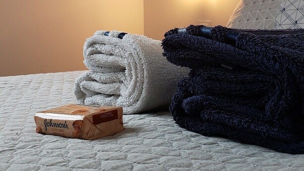 A neatly made bed with folded towels and a box of Johnson's baby lotion. - Apto na Pampulha próximo ao Mineirão  (Belo Horizonte)