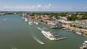 Un port de plaisance avec des bateaux amarrés, un grand yacht blanc et un pont en arrière-plan.