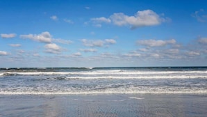 A beach with waves and a clear sky.