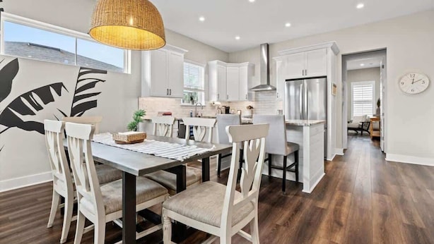 A modern kitchen with white cabinets, stainless steel appliances, and a dining area with a wooden table and chairs.
