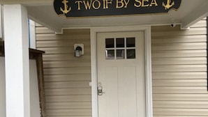 En hvid dør med et glasfelt og et skilt over, der siger "TWO IF BY SEA".