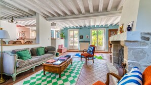 A spacious living room with a checkered rug, a sofa, a coffee table, and a fireplace. - Maison Prado - avec piscine privée et grand jardin (Magny-en-Vexin)