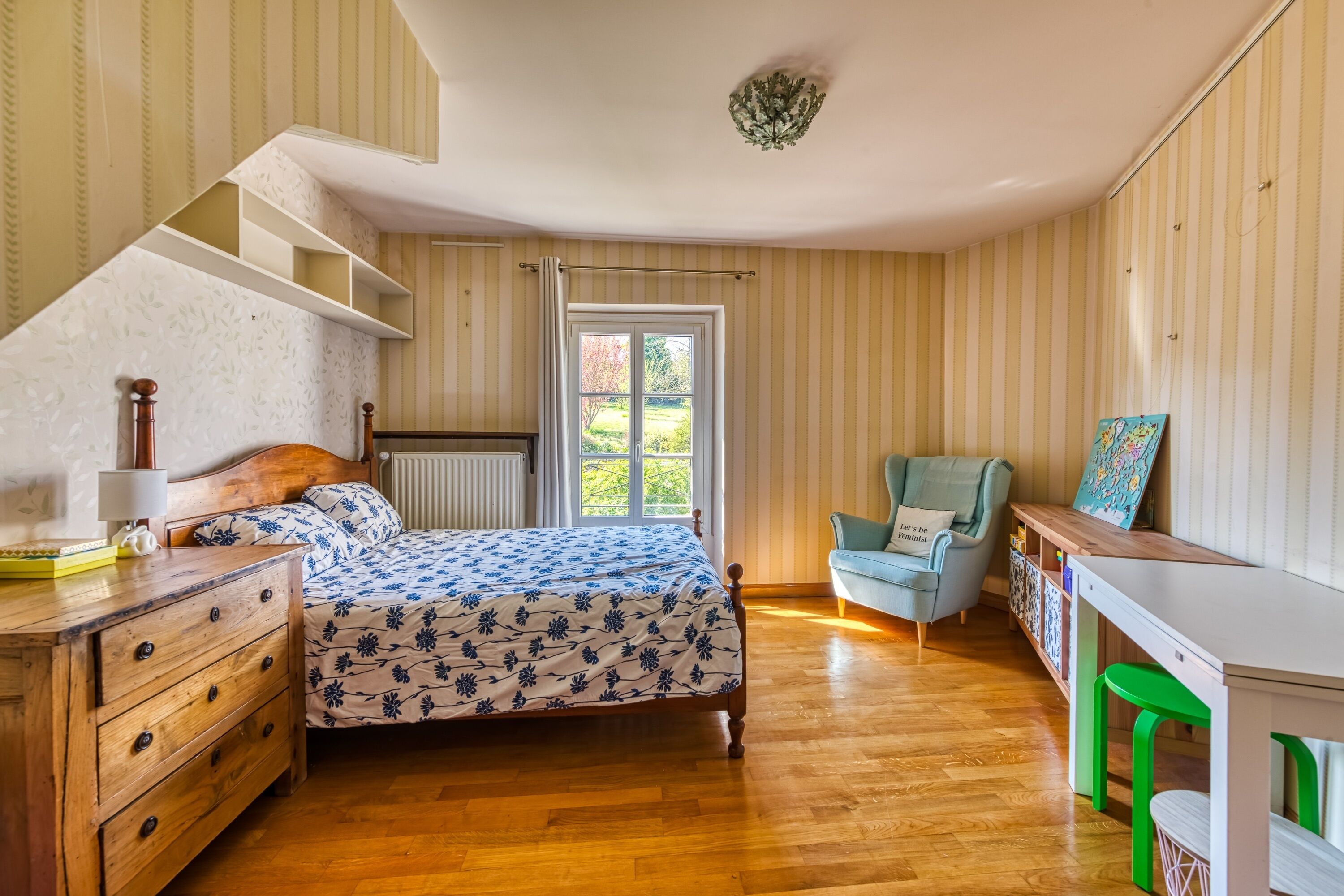 A bedroom with a wooden bed, a dresser, a chair, and a desk with a bookshelf.