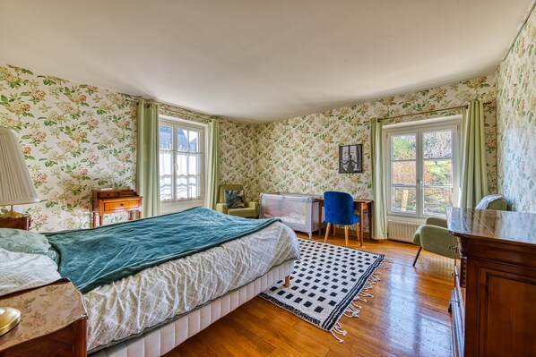 A bedroom with a bed, desk, chair, and a crib.