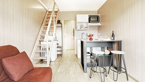 A compact living space with a kitchen area, a sofa, and a staircase.