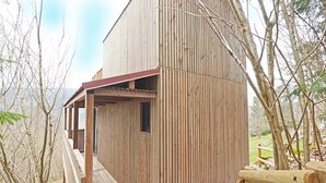 A wooden cabin with a balcony, surrounded by trees.