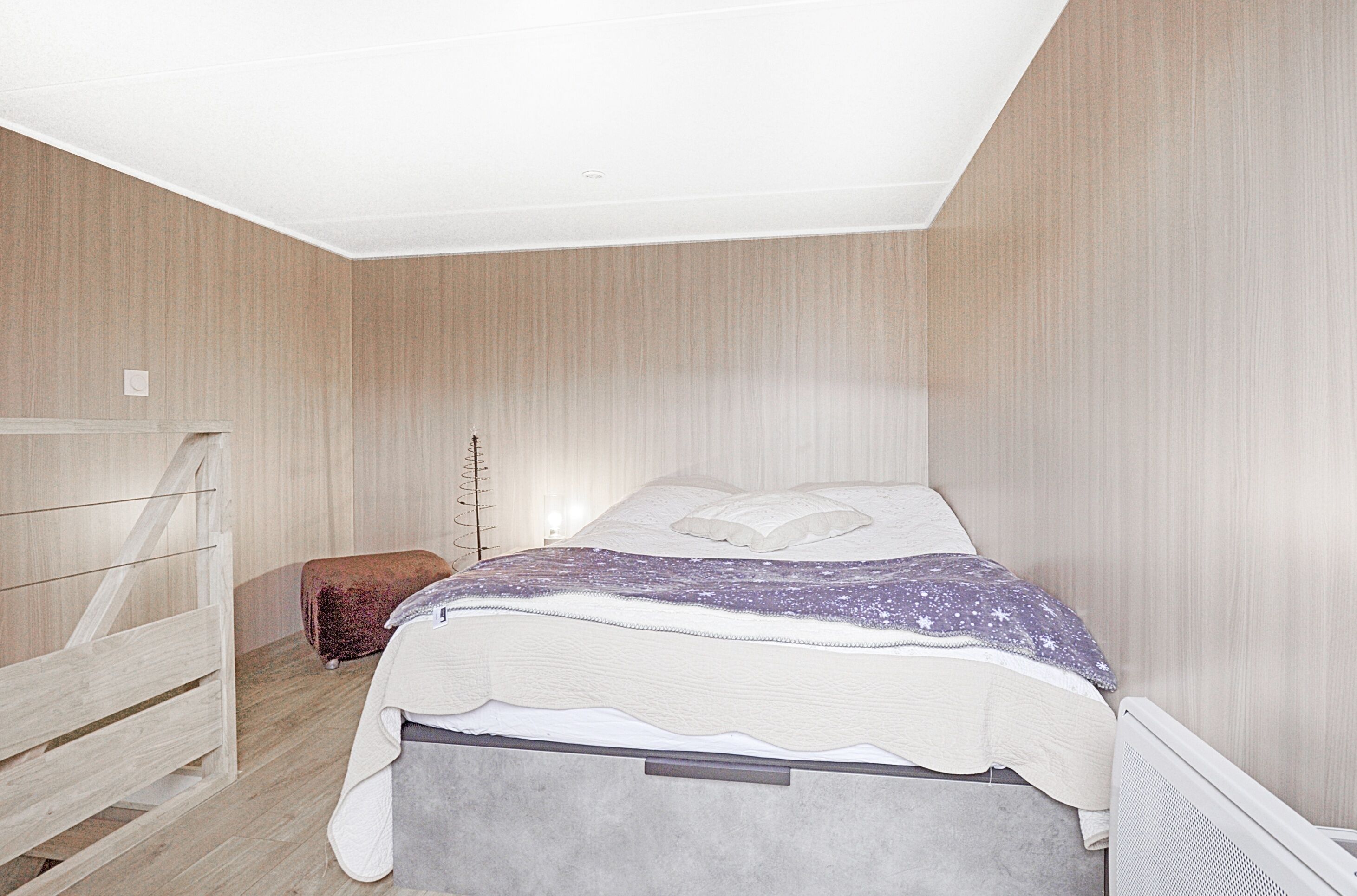 A bedroom with a bed, a wooden bench, and a radiator.