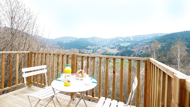 A wooden deck with a table and chairs overlooking a mountainous landscape.