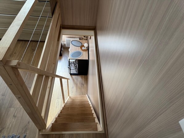 Un interior moderno con una escalera de madera que conduce a un comedor con una mesa redonda y sillas.