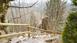 A wooden staircase leading up a mountain trail, surrounded by trees and rocky terrain.