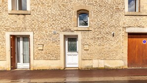 Un edificio de piedra con una puerta blanca, un ventanal pequeño y una puerta de madera.