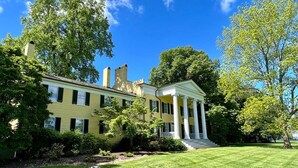 Un'ampia casa in stile coloniale, di colore giallo, con veranda e prato curato.