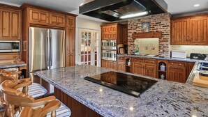 Una cucina moderna con mobili in legno, elettrodomestici in acciaio inossidabile, un piano di lavoro in granito e una penisola centrale con posti a sedere.