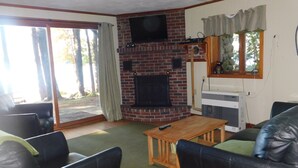 A living room with a fireplace, television, and seating area. - Peaceful Long Lake Escape – Dock, Kayaks, & Seasonal Charm (Naples)