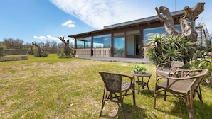 A modern house with large glass windows, a wooden deck, and wicker furniture in the yard. - 3326 Villetta Jannara by Barbarhouse (Melendugno)