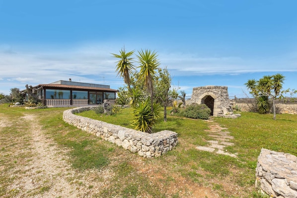 A house with a stone pathway, a stone archway, and a modern building with large windows.