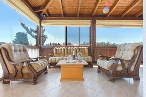 A wooden ceiling, a wooden table with a cushion, and a view through large windows.
